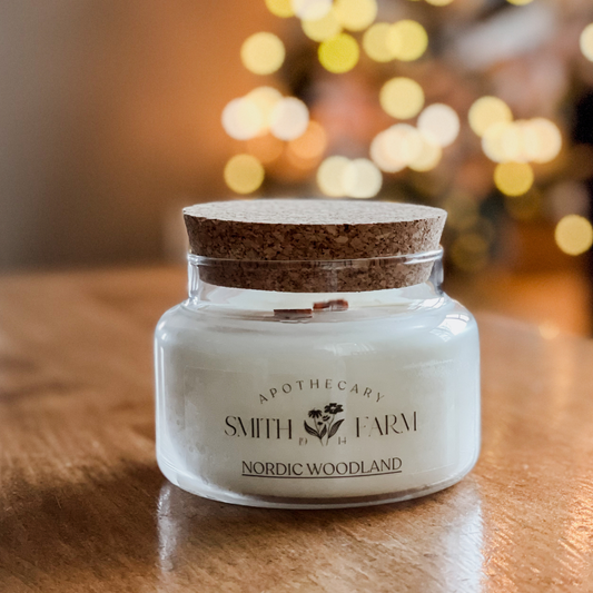 Candle in a glass jar with cork lid on a wooden surface, blurred lights in the background