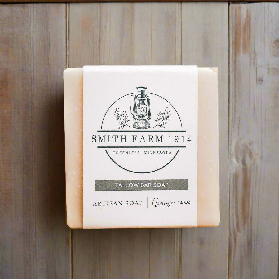 A bar of soap with a label that reads 'Smith Farm 1914 Tallow Bar Soap' placed on a wooden surface.