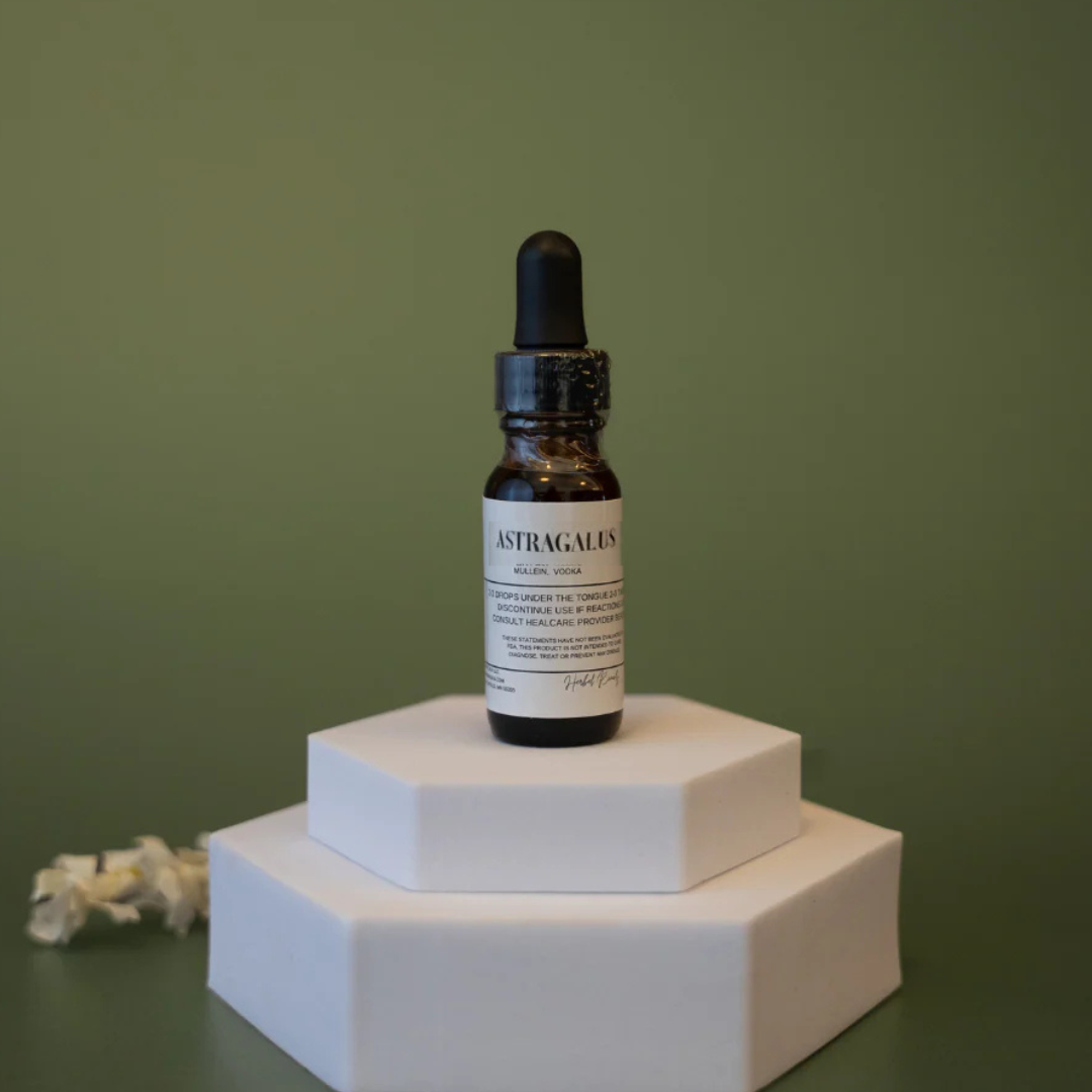 Bottle of Astragalus tincture on a white hexagonal stand against a green background