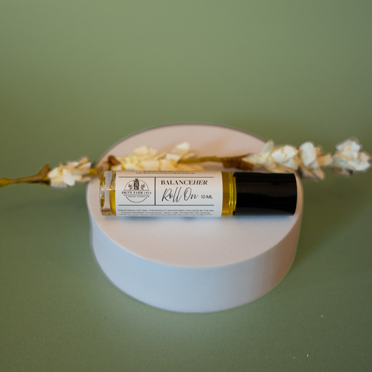 Roll-on bottle labeled 'Balance' on a round white platform with a green background