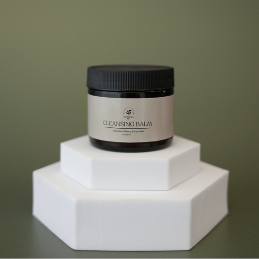 Cleansing balm jar on a white hexagonal stand against a green background