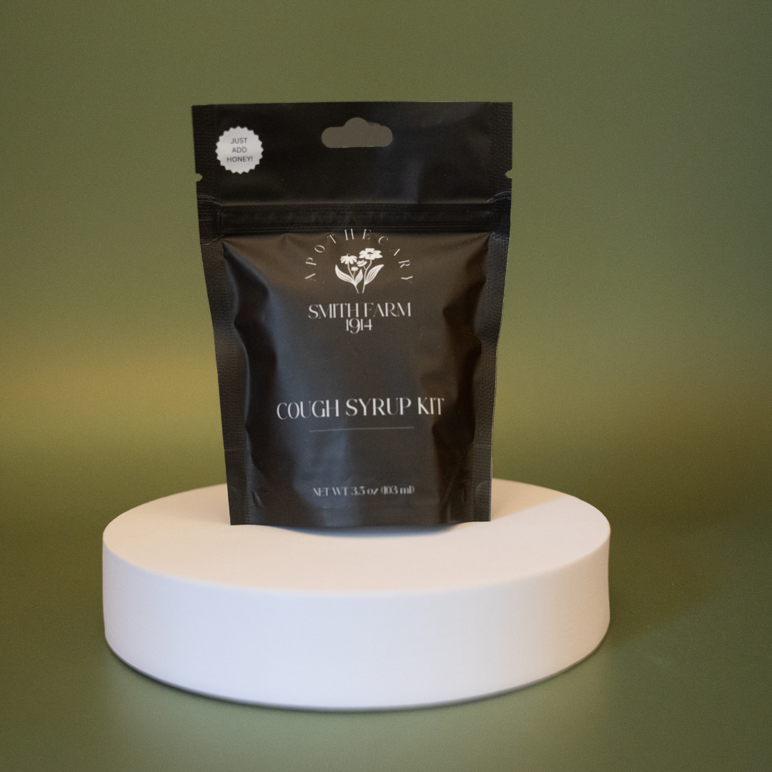 Black pouch labeled 'Cough Syrup Kit' by Smith Farm on a white stand with a green background