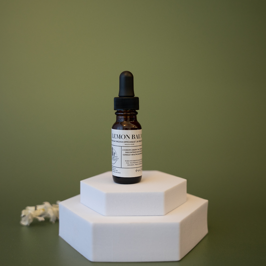 Bottle of lemon balm tincture on a white hexagonal stand against a green background