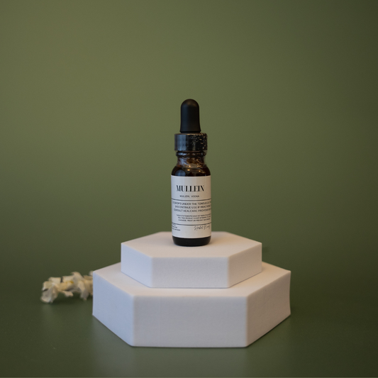 Bottle with dropper on a white hexagonal platform against a green background