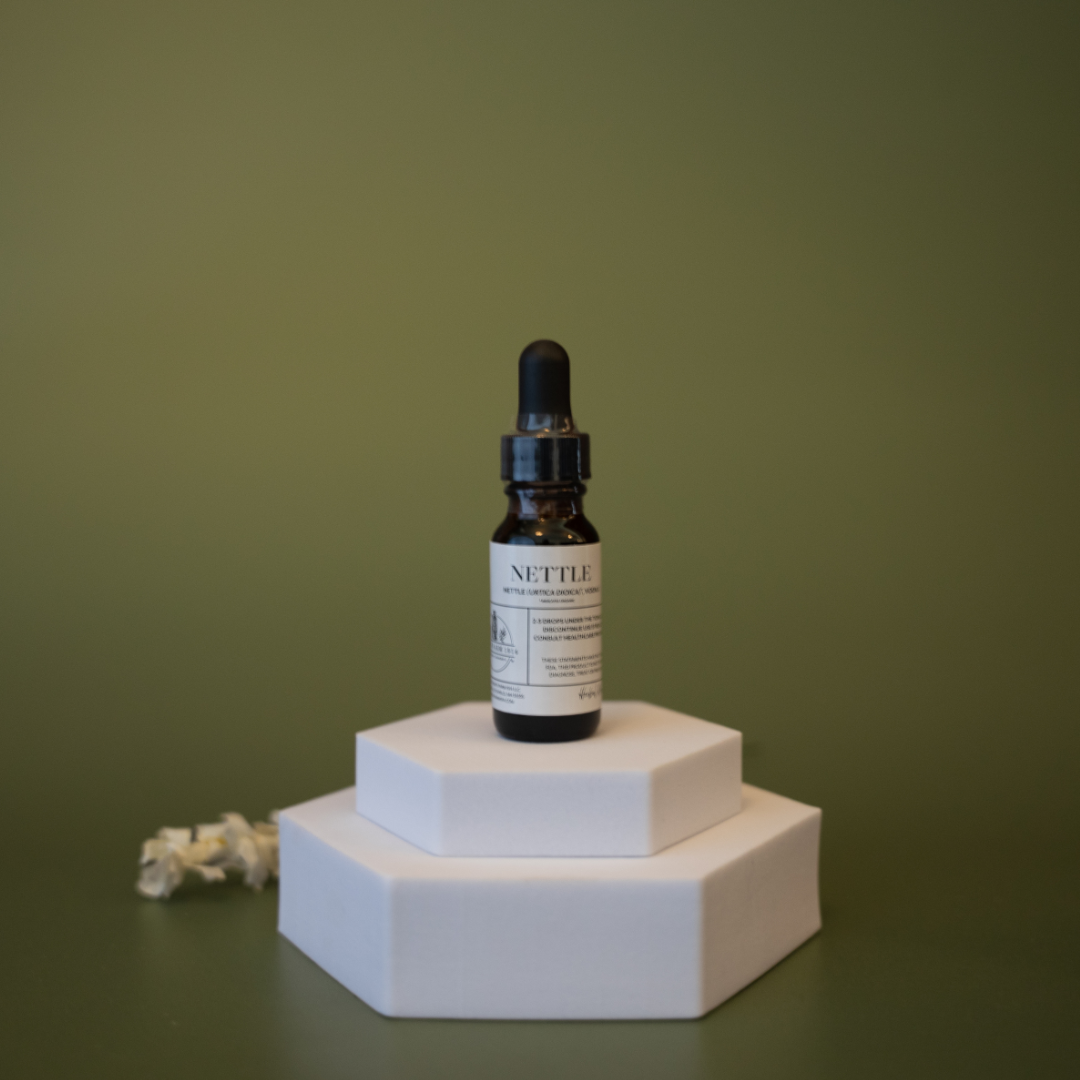 Bottle of Nettle tincture on a white hexagonal stand against a green background