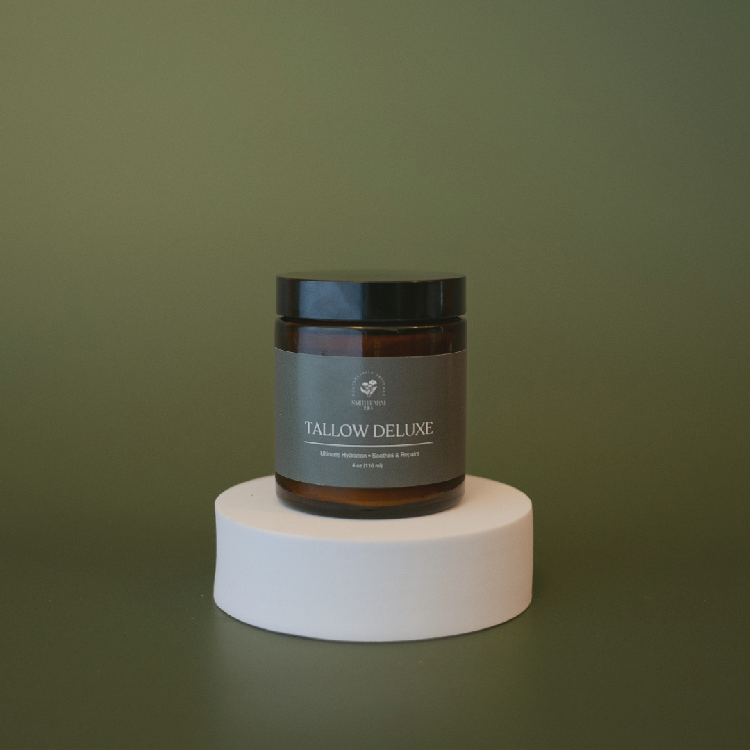 Jar of Tallow Deluxe on a white pedestal against a green background