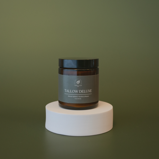 Jar of Tallow Deluxe on a white pedestal against a green background